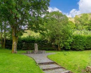 un parco con una panchina in pietra e un albero di Blue Hill Park ad Ambleside