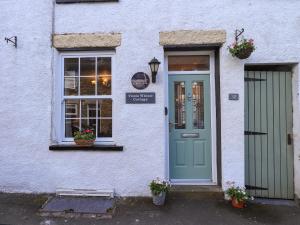 a white building with a blue door and windows at Tizzie Whizie Cottage in Windermere