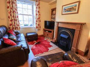 a living room with a leather couch and a fireplace at Tizzie Whizie Cottage in Windermere