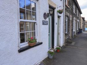 a building with flowers in a basket on a street at Tizzie Whizie Cottage in Windermere