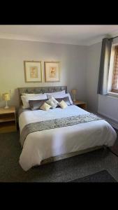 Llanwenarth Hotel في كريكهويل: غرفة نوم بسرير ابيض كبير مع مخدات