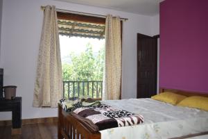 um quarto com uma cama e uma grande janela em Naisarga Hill View em Somvārpet