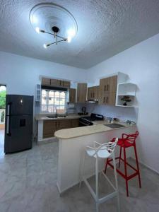 a kitchen with a refrigerator and a counter with two stools at Apartamento Céntrico en Cabrera in Cabrera