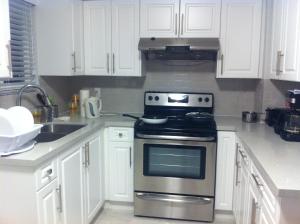 uma cozinha com um fogão de aço inoxidável e armários brancos em Edmonds Home em Burnaby