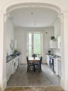 a large white kitchen with a table and chairs at St Paul's Road Townhouse by Clifton Short Lets in Bristol