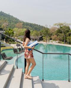 Perhentian Marriott Resort & Spa في بيرهينتيان: امرأة تقف على سور بالقرب من حمام السباحة