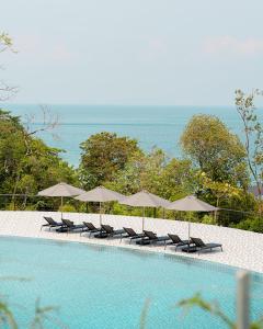 Perhentian Marriott Resort & Spa في بيرهينتيان: صف من الكراسي والمظلات بجانب المسبح