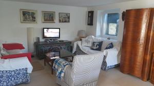salon z białymi krzesłami i telewizorem w obiekcie Rustic House Miketa - Family Summertime w mieście Lukoran