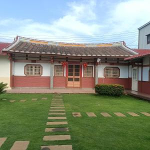 uma casa vermelha com um relvado à frente em J ancient house em Lucao