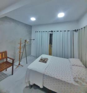- une chambre avec un lit blanc et une chaise dans l'établissement Suítes Modernas no Centro da Praia da Pipa, à Pipa