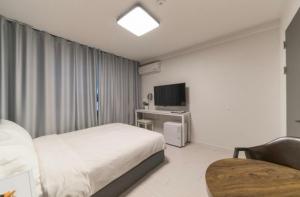 1 dormitorio con 1 cama, 1 silla y TV en La Famille, en Yangyang