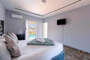 a bedroom with a large white bed and a television at The Crescent Victoria Falls in Victoria Falls