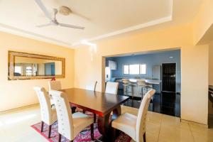 a dining room with a wooden table and white chairs at The Crescent Victoria Falls in Victoria Falls