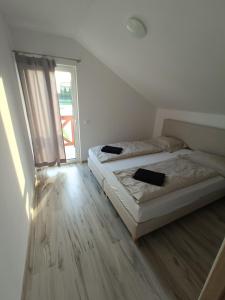 two beds in a white room with a window at Apartamenty Kwiat Jabłoni in Mikołajki