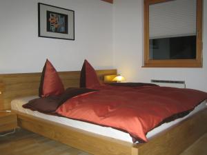 Schlafzimmer mit einem Bett mit roter Bettwäsche und einem Fenster in der Unterkunft Senda 517 C in Scuol