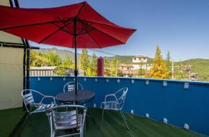 a table and chairs with a red umbrella on a balcony at Hotel Eat Dot Com Alpeuseu Oncheon in Ulsan