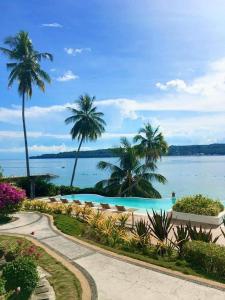 a swimming pool with palm trees and the water at Kembali CONDO Resort with Sea View in Davao City