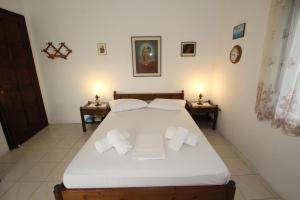 um quarto com uma cama com lençóis brancos e almofadas em Attainable Heaven by Frangki em Vathí