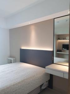 - une chambre avec un lit blanc et un miroir dans l'établissement Apartment Embarcardero Bintaro 1BR, à Jombang