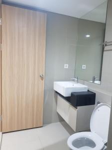 La salle de bains est pourvue d'un lavabo, de toilettes et d'un miroir. dans l'établissement Apartment Embarcardero Bintaro 1BR, à Jombang