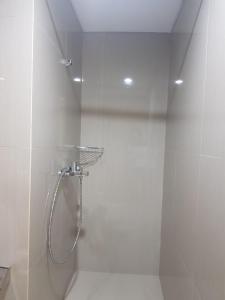La salle de bains est pourvue d'une douche avec une porte en verre. dans l'établissement Apartment Embarcardero Bintaro 1BR, à Jombang