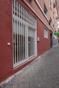 a red building with barred windows on a street at Madrid, Centro, Cuatro caminos A in Madrid