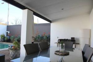 a patio with a table and chairs and a pool at Olive Grove on Provident in Cape Town