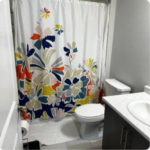 uma casa de banho com um WC e uma cortina de chuveiro de flores em Cozy Whitby Retreat em Whitby