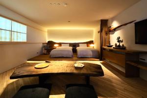 a bedroom with a bed and a table and a tv at MUKUten舎富士宮 MUKUtensha Fujinomiya natural wood retreat hotel in Fujinomiya