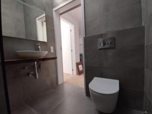 a bathroom with a white toilet and a sink at 28 Casa do Avô - 2Km from the beach in Sesimbra +13 photos
