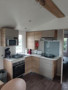 a kitchen with wooden cabinets and a stove top oven at SAS MHVACANCES LOUE MOBILHOME 2 CHAMBRES PROCHE CHATEAUX et ZOO BEAUVAL in Onzain