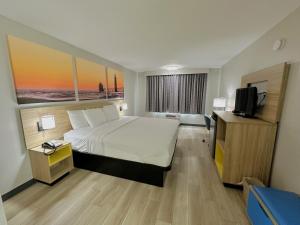 ein Hotelzimmer mit einem Bett und einem TV in der Unterkunft Days Inn by Wyndham Holland in Holland