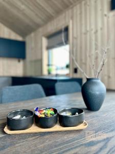 three bowls of food on a wooden table with a vase at Brand new cabin in the center of Skeikampen in Svingvoll
