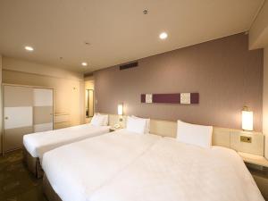 two beds in a hotel room with white sheets at Shinjuku Prince Hotel in Tokyo