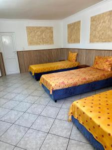 three beds in a room with yellow and orange sheets at Hanul Lui Ionut in Satu Mare