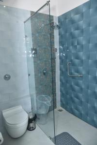 a bathroom with a toilet and a glass shower at Adrushya- Suites & Villas by MLS in Mukteswar