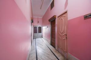 un pasillo vacío con paredes rosas y una puerta en OYO Hotel 65035 Maa Laxmi Lodge en Bānkura