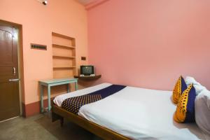 1 dormitorio con cama, mesa y TV en OYO Hotel 65035 Maa Laxmi Lodge en Bānkura