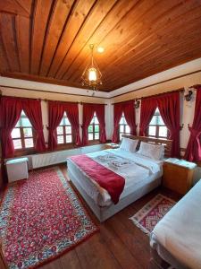 1 dormitorio con 1 cama grande y cortinas rojas en Muhsin Bey Konağı, en Safranbolu
