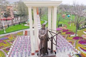 a statue of a man standing in front of a field of flowers at Apart Khujand in Khujand