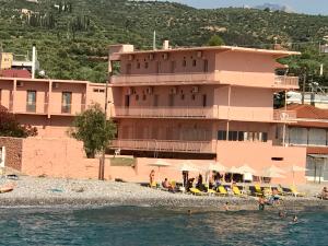 un grande edificio rosa su una spiaggia vicino all'acqua di Laas ad Avía