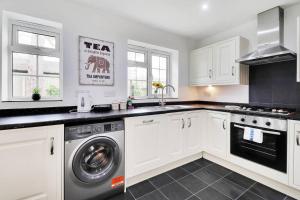 a kitchen with white cabinets and a washer and dryer at Pass the Keys Cute cottage in Pembury with parking in Pembury