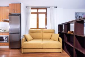 uma sala de estar com uma cadeira e um frigorífico em Apartamentos Turísticos Distrito Romano em Cartagena