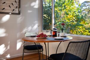 a table with a bowl of fruit in front of a window at Daylesford Spa Villa 5 in Daylesford