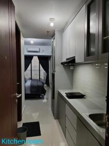 a kitchen with white cabinets and a bed in the background at Comodo Apartemen Pollux Habibie Rooftop-SeaView in Batam Center