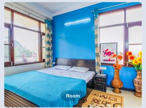 niebieska sypialnia z łóżkiem i dwoma oknami w obiekcie Shriya home stay Palampur w mieście Palampur