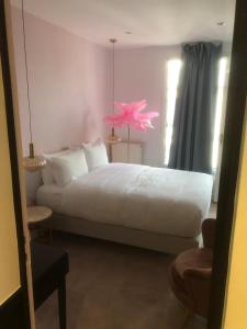 a bedroom with a white bed with a pink flower on it at Le Glam's Hotel in Paris