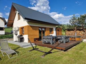 a house with a deck with a grill and a table at Domek w Paszynie - Sauna i Gorąca balia in Paszyn