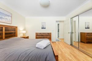 - une chambre avec un grand lit et une porte coulissante en verre dans l'établissement 1-3A Montague Street, Narooma, à Narooma