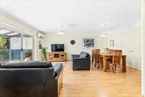 ein Wohnzimmer mit einer Couch und einem Tisch und Stühlen in der Unterkunft 1-3A Montague Street, Narooma in Narooma